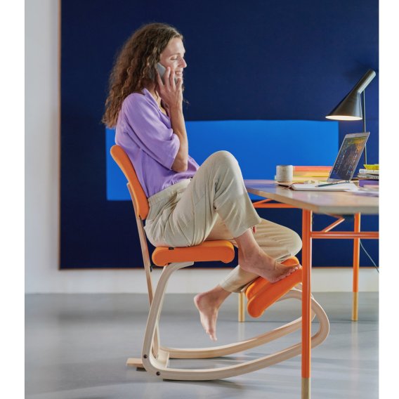 Frau sitzt entspannt auf dem Varier Variable Plus Kniestuhl mit R&uuml;ckenlehne im Home-Office