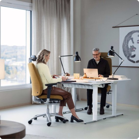 Modernes Paar im stilvoll eingerichteten minimalistischen Office am Schreibtisch auf ihren rh Logic 220 sitzend und am arbeiten.