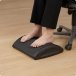 Im B&uuml;rostuhl sitzende Frau nutzt die Fu&szlig;reflexzonenmassagefunktion des HAG Quickstep.