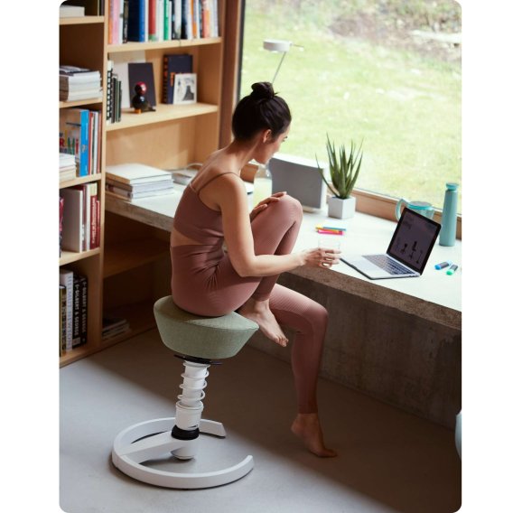 Junge Frau in einer entspannten Sitzhaltung auf dem Aeris Swopper in ihrem Arbeitszimmer.