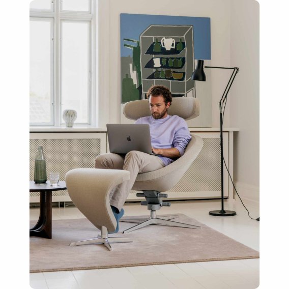 Mann sitzt mit einem Laptop auf dem Scho&szlig; im Varier Peel Designer Loungesessel.