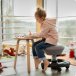 Kind auf einem Aeris Swoppster Kinderhocker mit schwarzem Gestell und grauem Bezug sitzend und malen.